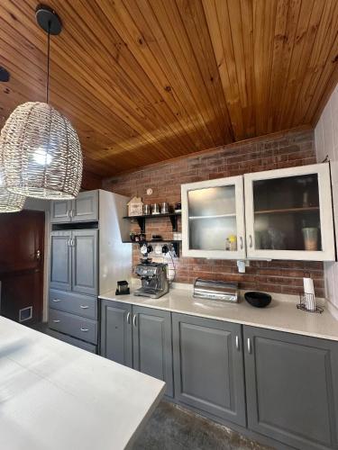 a kitchen with gray cabinets and a wooden ceiling at Mario & Luiza's Place - Cozy Stay with Pool & Braai in Worcester