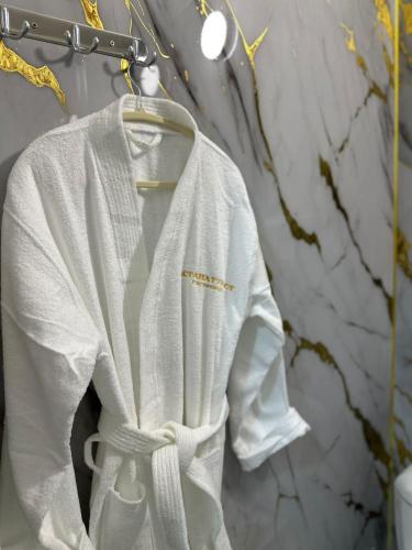 a white robe hanging on a wall in a bathroom at Турист in Astana