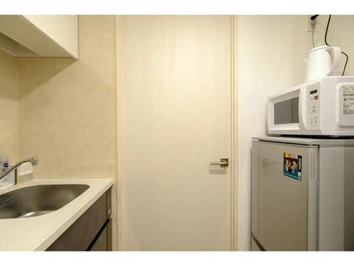 a kitchen with a sink and a microwave on top of a refrigerator at ZOOM Esaka Park - Vacation STAY 17110 in Suita