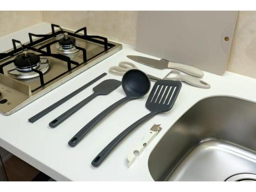 a kitchen counter with a stove with utensils on it at ZOOM Esaka Park - Vacation STAY 17111 in Suita