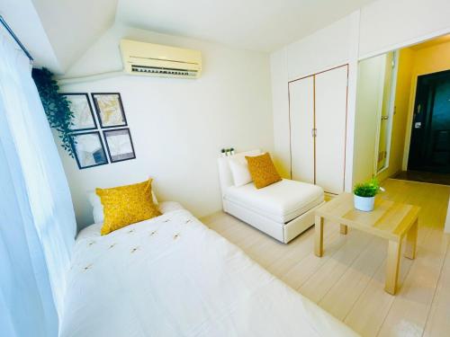 a white room with a bed and a chair at Sakura Apartment - Vacation STAY 17210 in Toyonaka
