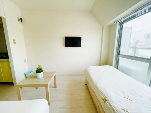 a bedroom with two beds and a table with a tv at Sakura Apartment - Vacation STAY 17210 in Toyonaka