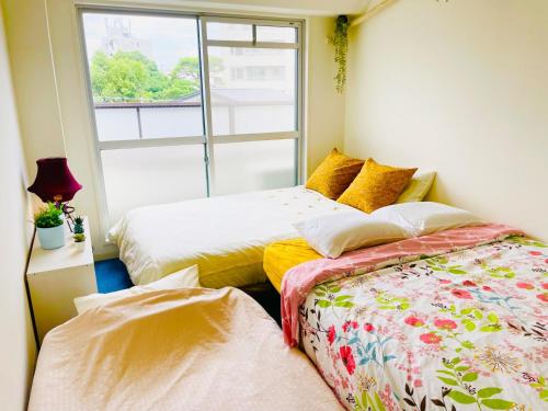 two beds in a room with a window at Sakura Apartment - Vacation STAY 17197 in Toyonaka