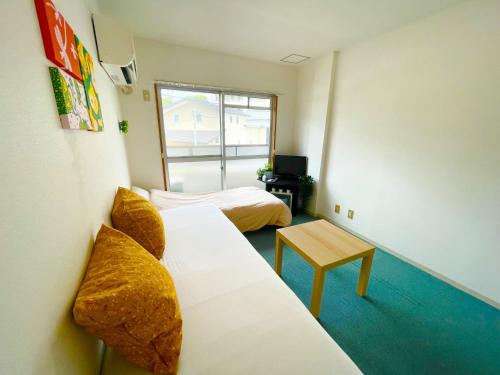 a room with two beds and a couch and a table at Sakura Apartment - Vacation STAY 17193 in Toyonaka