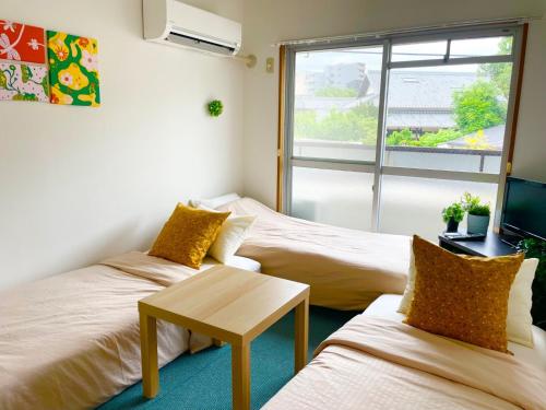 two beds in a room with a table and a window at Sakura Apartment - Vacation STAY 17193 in Toyonaka