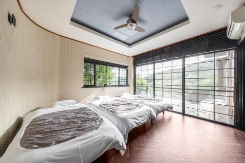 two beds in a bedroom with a ceiling fan at Momijisanso - Vacation STAY 36390v in Izu