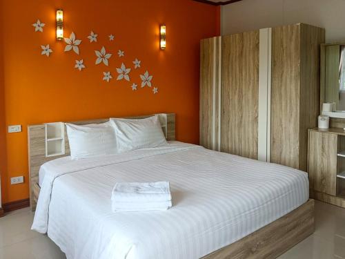 a bedroom with a large white bed with an orange wall at Rueanchorfa in Nong Bua Lamphu