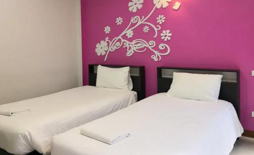 two beds in a room with a purple wall at Rueanchorfa in Nong Bua Lamphu