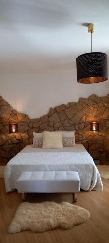 a bedroom with a bed with a stone wall at Casa de Freixo in Freixo de Espada à Cinta