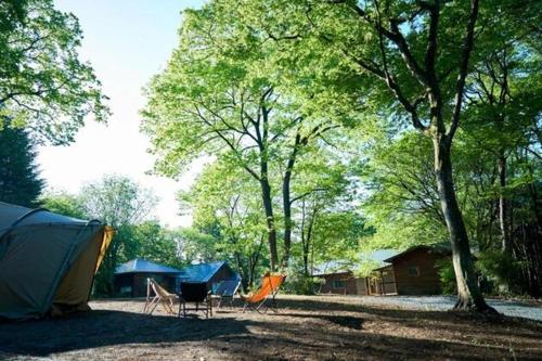 a tent and chairs in front of a group of trees at THEIR SATOYAMA FIELD - Vacation STAY 29945v in Kurobane