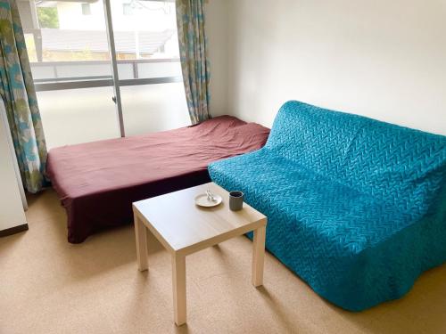 a room with a bed and a blue chair and a table at Sakura Apartment - Vacation STAY 17178 in Toyonaka