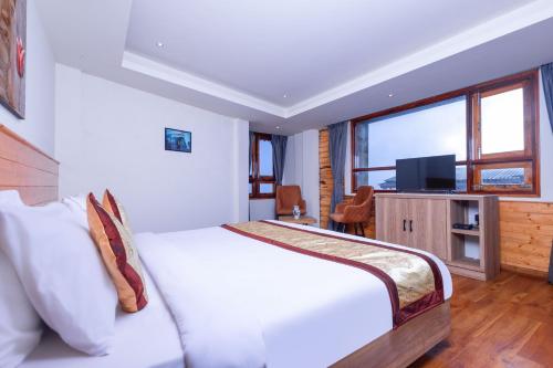 a bedroom with a white bed and a television at Sumitel Sanderling 500 meters from Mall Road in Darjeeling
