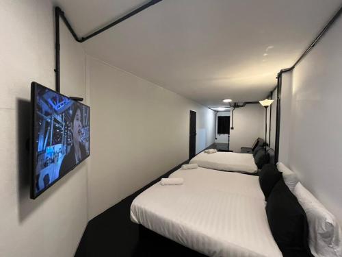 a room with two beds and a tv on the wall at 2Sleep DMK Airport Bangkok in Ban Ko