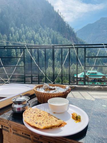 a plate of food on a table on a balcony at Trippy Homestay in Kasol