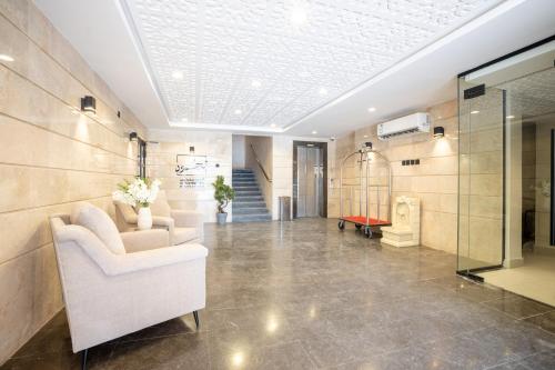 a lobby with a white chair and a glass cage at Aljood Residence-BY CH in Al Madinah