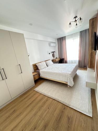 a white bedroom with a bed and a large window at Artima Downtown in Chişinău