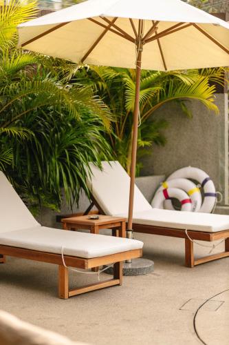 two lounge chairs with an umbrella and a beach ball at 涠洲岛隐拙山与澜海景酒店 in Weizhouxu