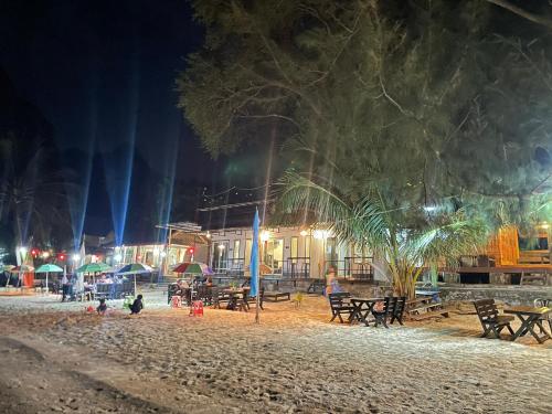 a beach at night with picnic tables and a building at Wangsarai Resort and Restaurant วังสาหร่าย รีสอร์ต และ ร้านอาหาร in Don Sak