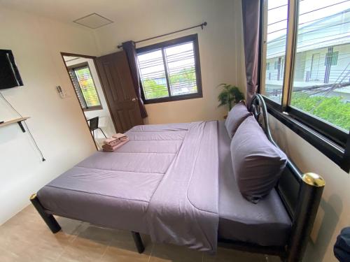 a bedroom with a bed with purple sheets and a window at Fran Sim Da Guest House in Bang Tao Beach