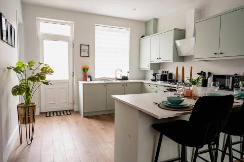a kitchen with white cabinets and a table with chairs at Modern Skipton House, Sleeps 5, Canal & Parking in Skipton