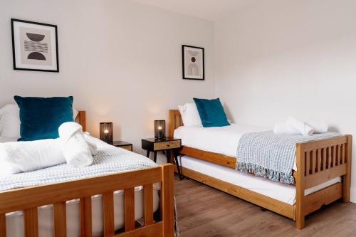 two beds in a room with blue and white pillows at Modern Skipton House, Sleeps 5, Canal & Parking in Skipton