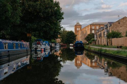 a canal with boats in a city with buildings at Modern Skipton House, Sleeps 5, Canal & Parking in Skipton