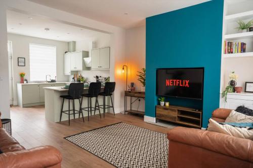 a living room with a kitchen and a blue wall at Modern Skipton House, Sleeps 5, Canal & Parking in Skipton