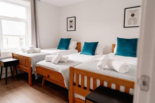 three beds in a room with blue and white pillows at Above Rubies - Sawley Cottage, Canal, Cafes, Bars! in Skipton