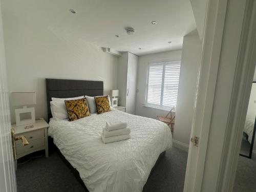 a bedroom with a white bed with pillows and a window at House by the Sea, Worthing in Worthing