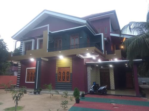 a house with a motorcycle parked in front of it at Nilmini Rooms rand in Kalpitiya