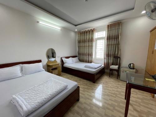 a bedroom with a bed and a desk and a window at Khách sạn Đông Tây Quy Nhơn in Quy Nhon