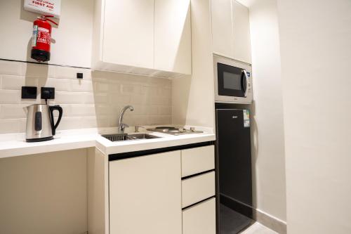a small kitchen with a sink and a microwave at Aljood Residence-BY CH in Al Madinah