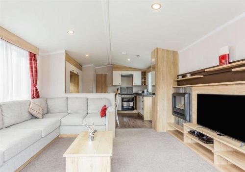 Una sala de estar con un sofá blanco y un televisor. en Sanctuary 10 Hot tub lodge, en Fort Augustus