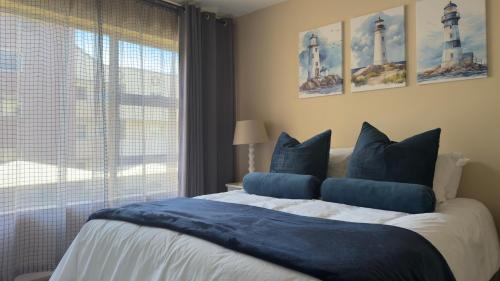a bedroom with a bed with blue pillows and a window at Stylish stay at Hartensee in Mossel Bay