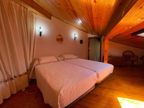 a bedroom with a bed in a room with wooden ceilings at La Casina del Arroyo in Poo de Cabrales