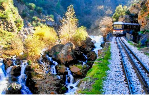 a train traveling down the tracks next to a waterfall at Akrata Golden Beach House 2 in Aíyira