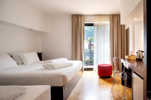 a hotel room with two beds and a desk at Astoria Resort in Riva del Garda