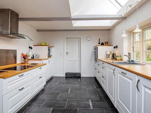 a kitchen with white cabinets and black tile floors at 8 person holiday home in Fur in Fur