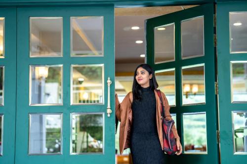 a woman is standing in front of doors at Hotel C7 Munnar in Munnar