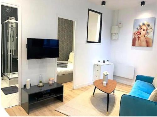 Una sala de estar con un sofá azul y una mesa. en Joli Appart 4pers#Buttes Chaumont#Chapeau Rouge, en París