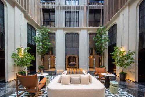 a hotel lobby with a bed and tables and chairs at Beijing Wangjing 798 Art District Yifei Hotel in Beijing
