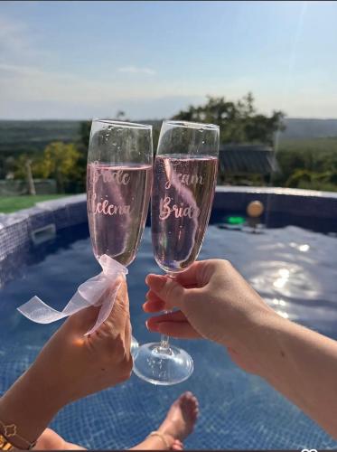 due persone che tengono in mano dei bicchieri di vino accanto a una piscina di Vila Sofia - Pool, Sauna & Nature Escape a Varna