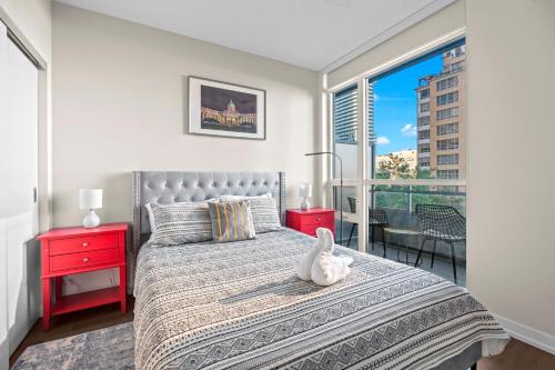 a bedroom with a bed with a red night stand and a window at luminous 2-Bedroom Apartment with Balcony in Toronto