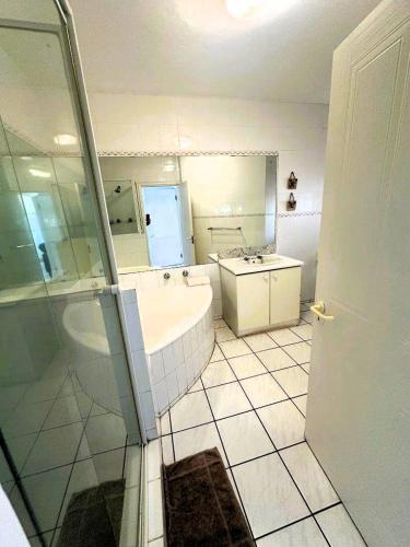 a bathroom with a tub and a sink and a mirror at Tahiti Dreaming in Umdloti