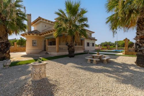 a house with palm trees in front of it at Fields & Beachside Villa by Fidalsa in Jacarilla
