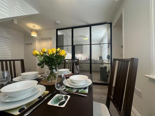 a dining room table with a vase of yellow flowers at House by the Sea, Worthing in Worthing