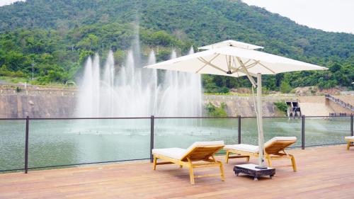 two chairs and an umbrella in front of a fountain at Swiss-Belvillas Solavita Binh Tien in Binh Tien