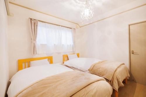 two beds in a room with a window at Hot Spring Cottage "Stella" - Zao Sansuien - Gaia - Vacation STAY 54020v in To-katta