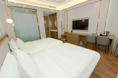 a hotel room with a white bed and a television at 万信至格酒店乌鲁木齐机场德港万达店 in Ürümqi