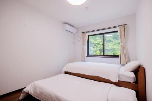 two beds in a room with a window at Re Start - Hot Spring Villa - Zao Sansuien Gaia Re - Vacation STAY 54075v in To-katta
